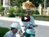 Vừa lái xe máy vừa… đội bánh trên đầu